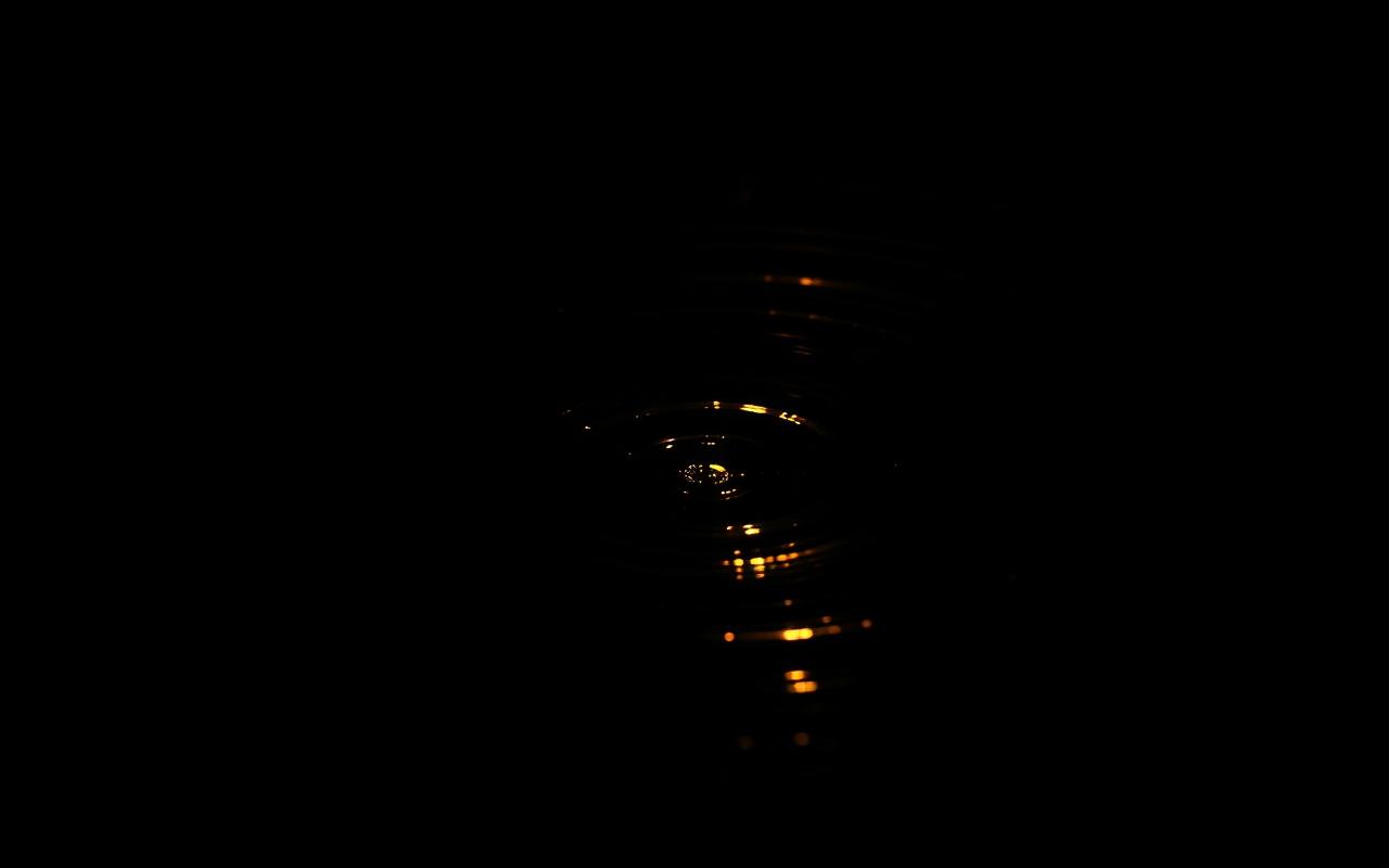 Onde dorée concentrique sur eau noire immobile — métaphore d'un système nerveux qui retrouve son rythme.